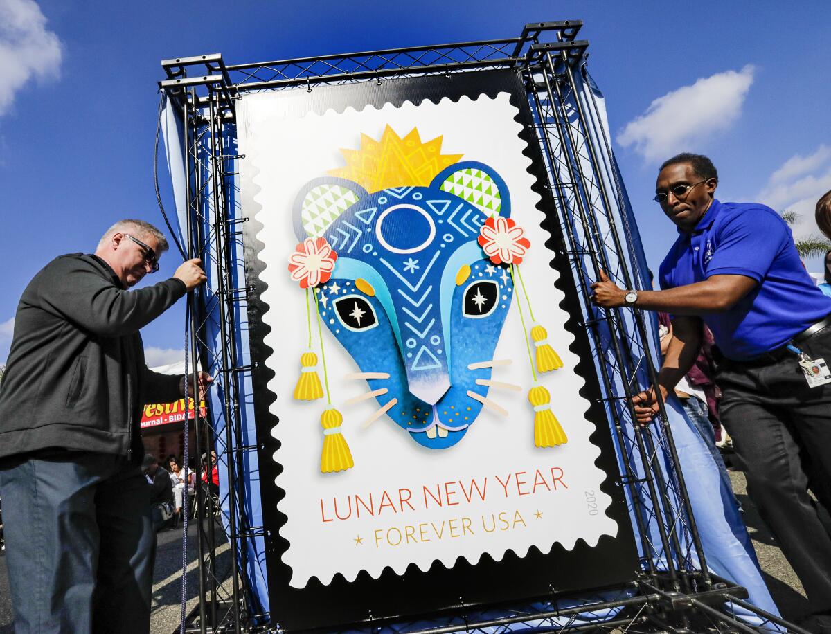 Michael Henry and Charles Williams of the U.S. Postal Service move a replica of the Year of the Rat forever stamp