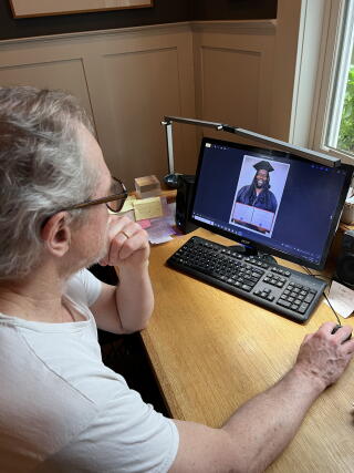 A man sits at a desk looking at a computer screen.