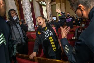 Los Angeles , CA - January 17: Michael Williams, left, and Black Lives Matter co-founder Melina Abdullah protest the presence of city council Kevin de Leon at the city council meeting at City Hall on Tuesday, Jan. 17, 2023 in Los Angeles , CA. (Irfan Khan / Los Angeles Times)