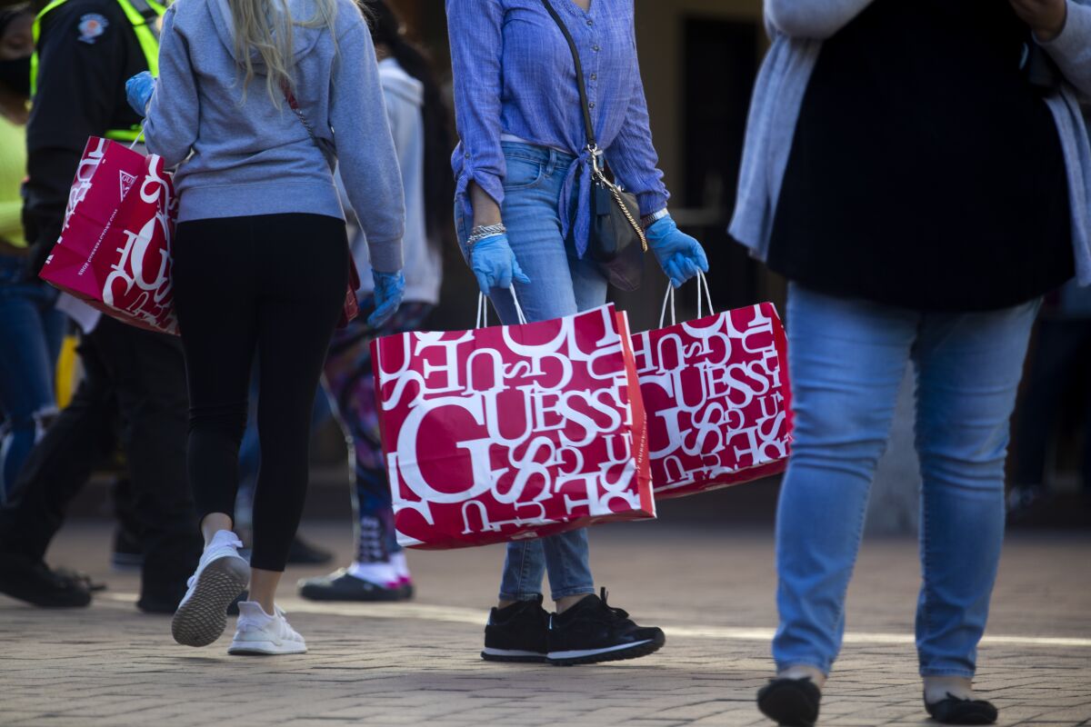 People carry red Guess shopping bags at an outdoor mall