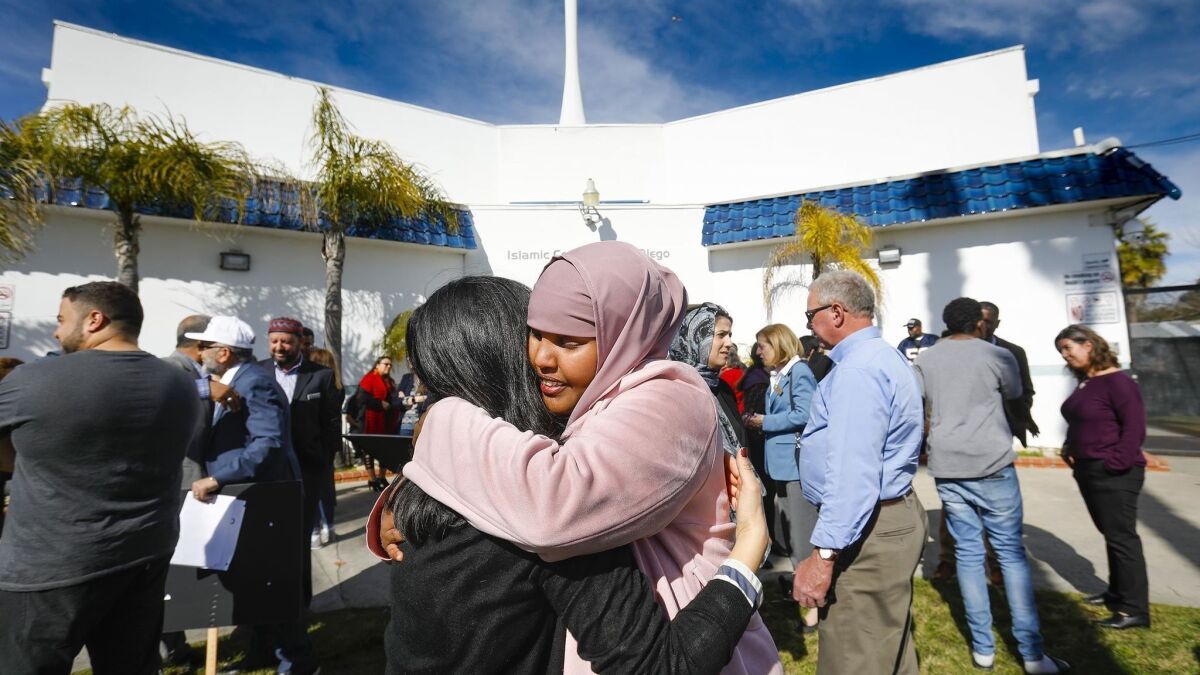 Carol Kim, left, of the San Diego Building Trades Council and Ismahan Abdullahi, right, an organizer of a news conference hosted by Muslim Leadership Council of San Diego denouncing mass shootings at two mosques in New Zealand, embrace at the Islamic Center of San Diego.