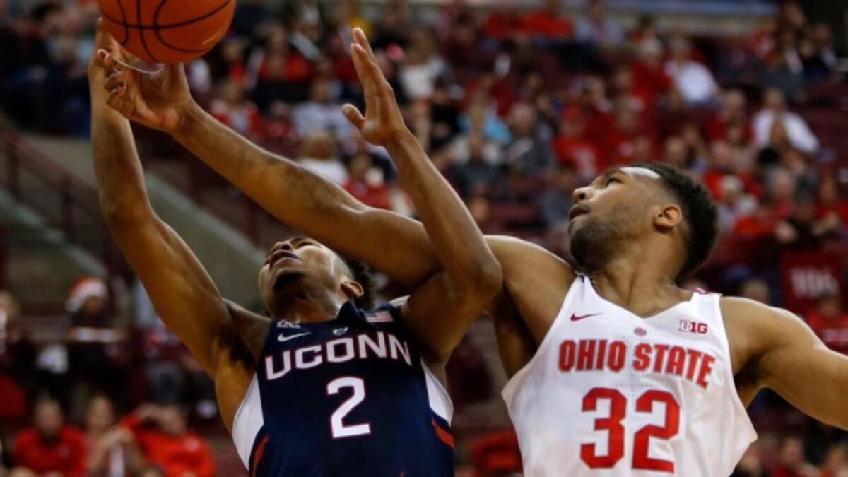 Ohio State big man Trevor Thompson grabs a rebound in front of Connecticut guard Jalen Adams during the first half of a game on Dec. 10.