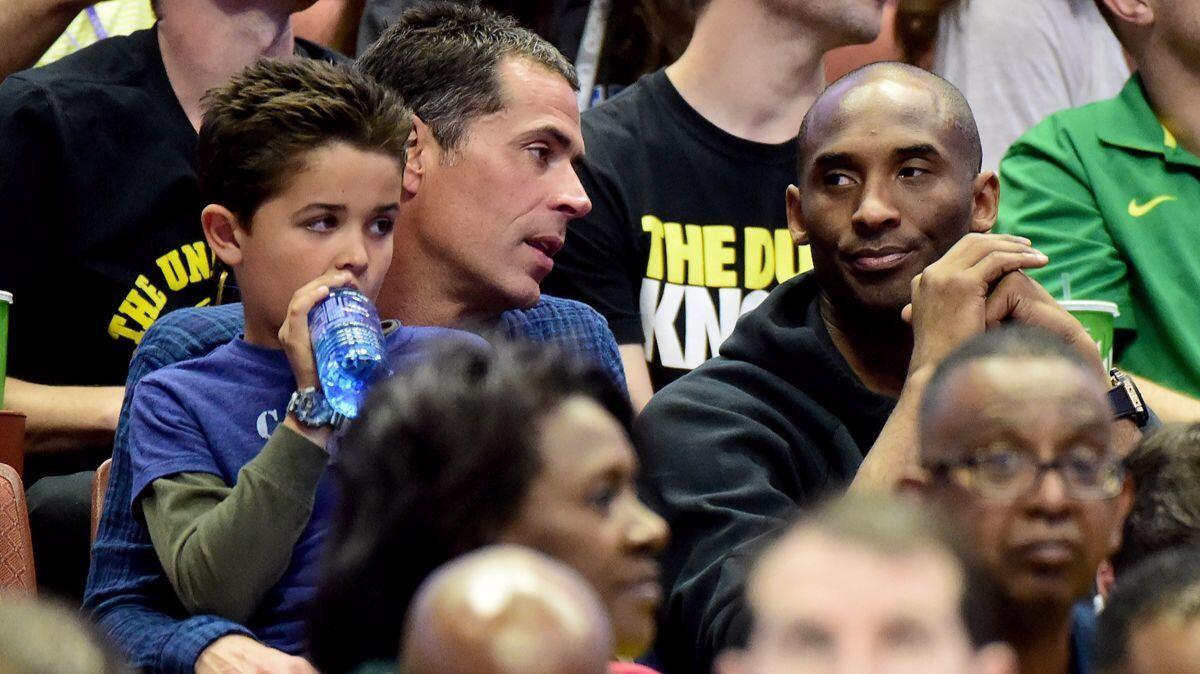 Rob Pelinka talks with Kobe Bryant during an NCAA men's basketball tournament game at Honda Center on March 26, 2016.