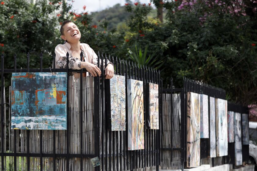LOS ANGELES, CA - APRIL 17, 2020: Artist Olivia Arthur hangs her artwork on her fence and neighbors' fences as a drive-by gallery of sorts in her Northeast Los Angeles neighborhood. She has been doing this for about three years, since she started painting, and during the coronavirus pandemic it gives passers by some art to enjoy. (Myung J. Chun / Los Angeles Times)