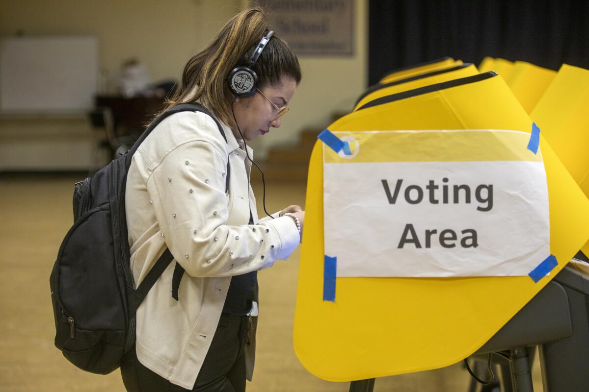 A woman stands in front of a voting machine