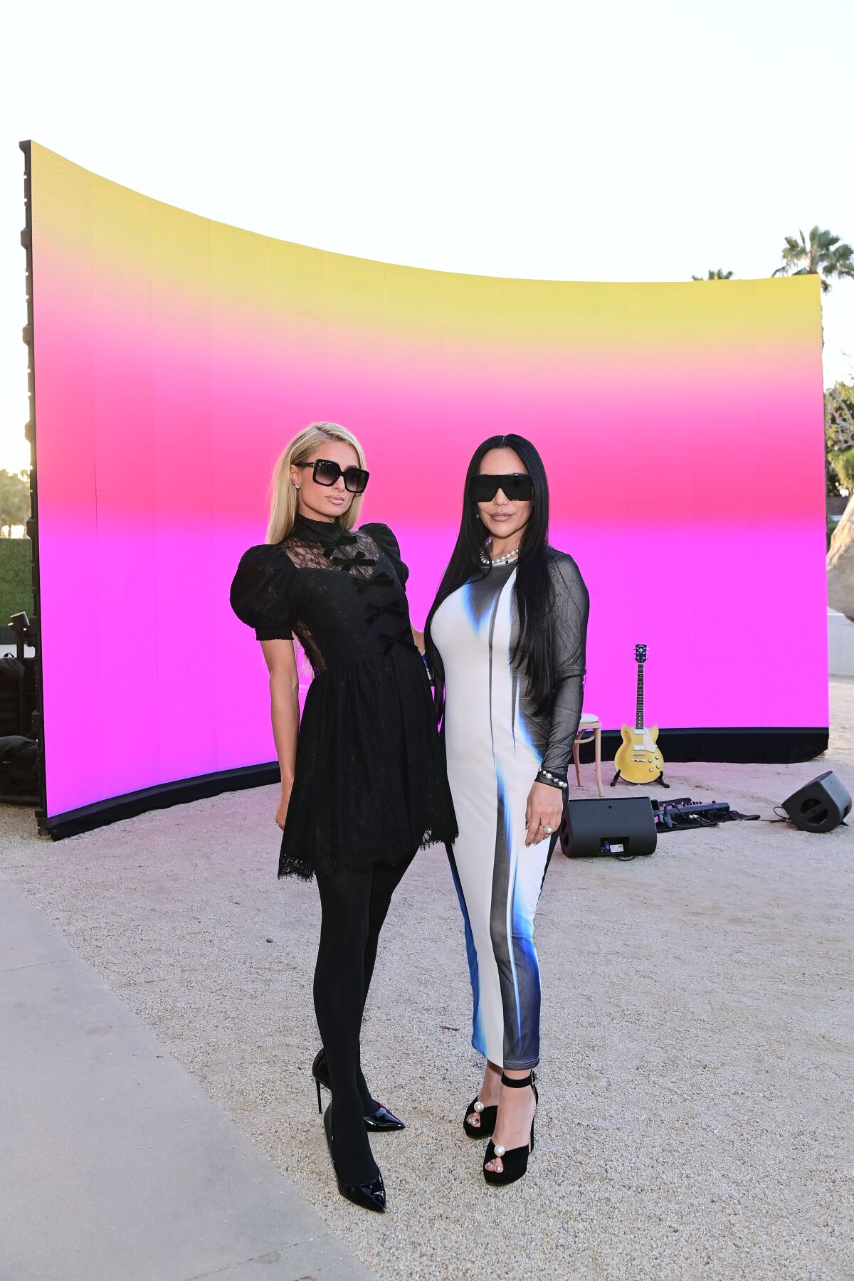 Two women stand before a colorful backdrop.