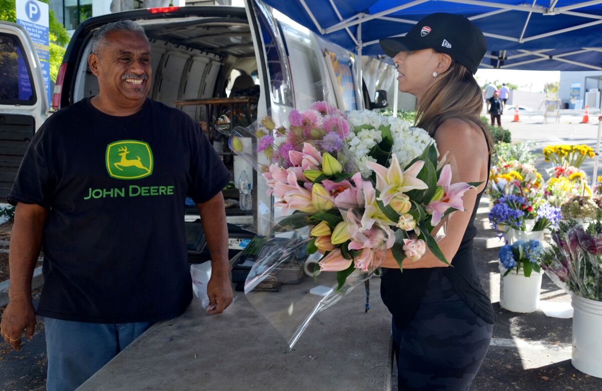 Flower farmer David Franco helps Rose Maniscalchi with her selection at the Corona del Mar farmers market.