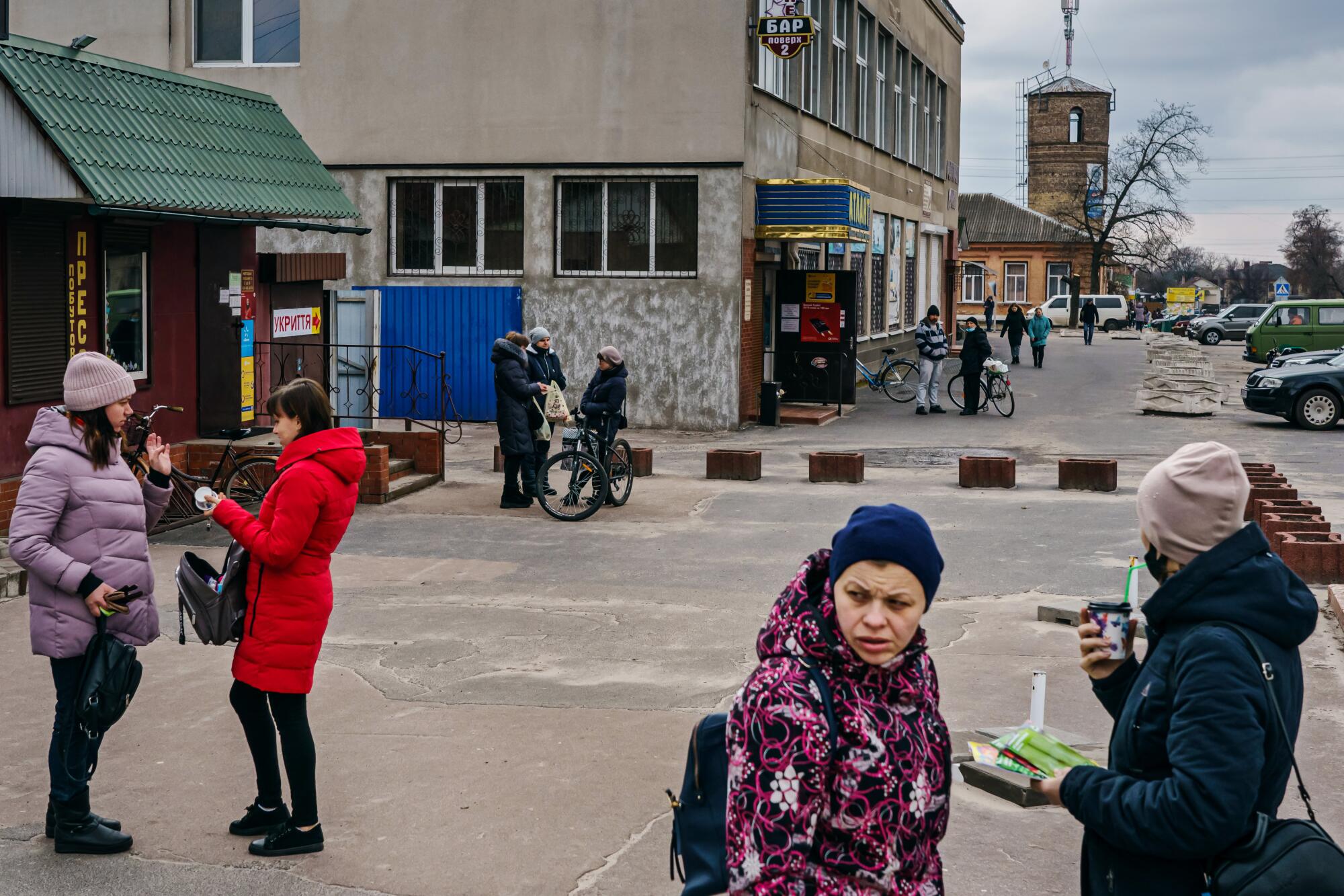 Local residents get supplies and wait for food distribution at the center of town in Oster, Ukraine