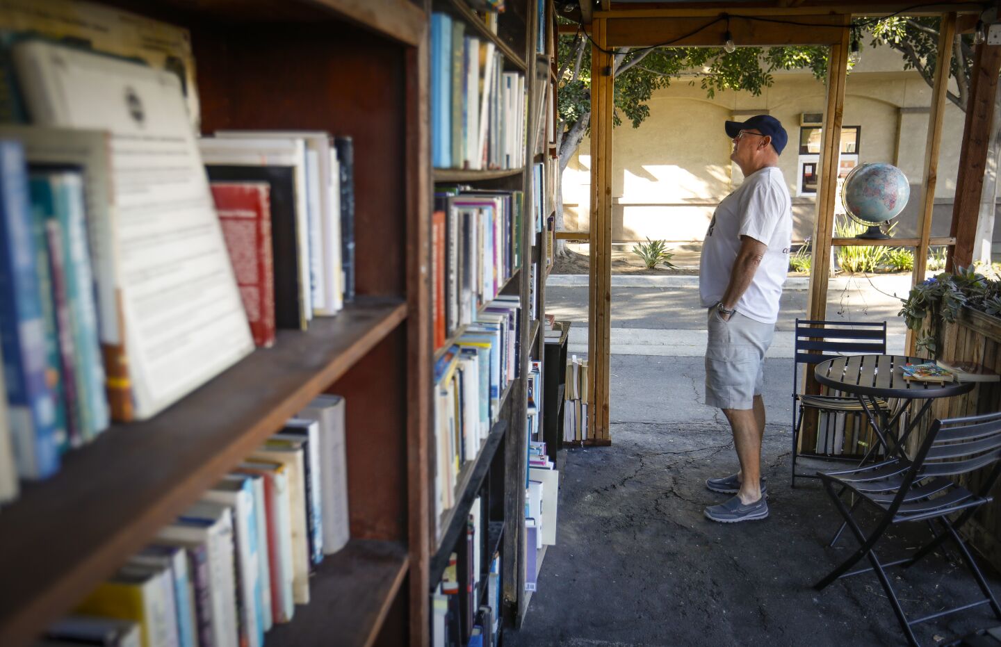 Mike Riege of Vinton, Iowa browses the books in the community library portion of Lhooq Books, outside the funky vintage bookstore in Carlsbad Village. Sean Christopher, the owner recently received a 60-day eviction notice for both the shop and the adjoining house where he has raised his son, alone. He's hoping to achieve a stay of eviction on the property long enough to sell off his book inventory and find a new space without going bankrupt and ending up homeless with his son.