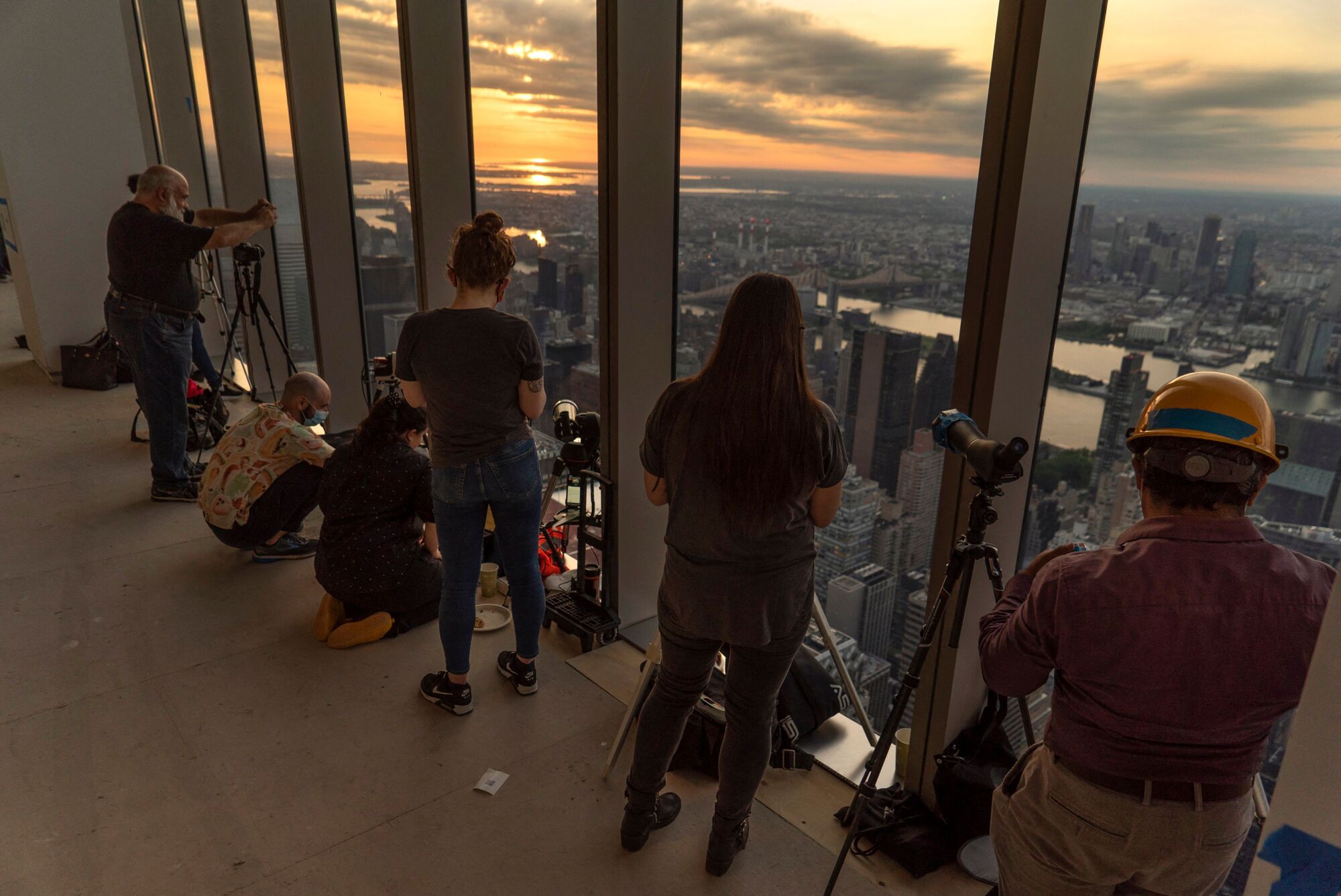 Amateur astronomers watch as the sun rises partially eclipsed in New York City.