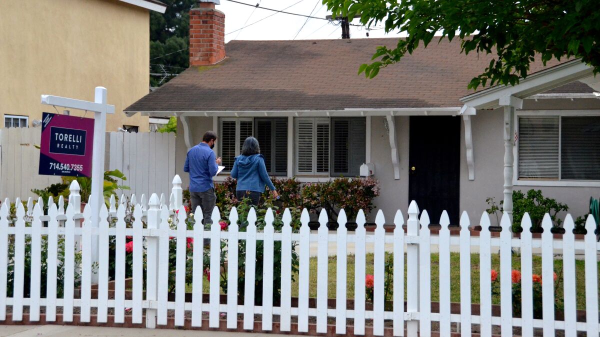 A real estate agent escorts his client into a home for sale in Costa Mesa on Saturday, April 24, 2021.