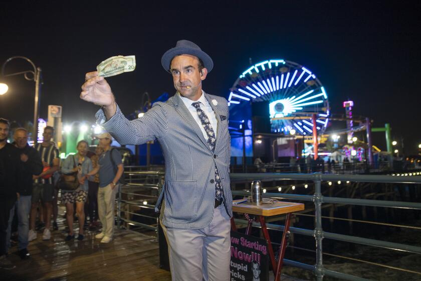 SANTA MONICA, CALIF. -- TUESDAY, SEPTEMBER 17, 2019: Magician Frank DeVille, of Santa Monica, performs magic tricks before a crowd on the Santa Monica Pier after being selected out of a daily lottery in Santa Monica, Calif., on Sept. 17, 2019. To be a street performer on the Santa Monica Pier, it helps to be lucky. There are only 24 designated spaces on the pier, and on a summer weekend there can be 50 or more performers at the 5:00 pm lottery drawing. (Allen J. Schaben / Los Angeles Times)