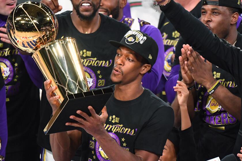 Rajon Rondo is surrounded by his teammates as he holds the trophy after the Lakers won the 2020 NBA championship.