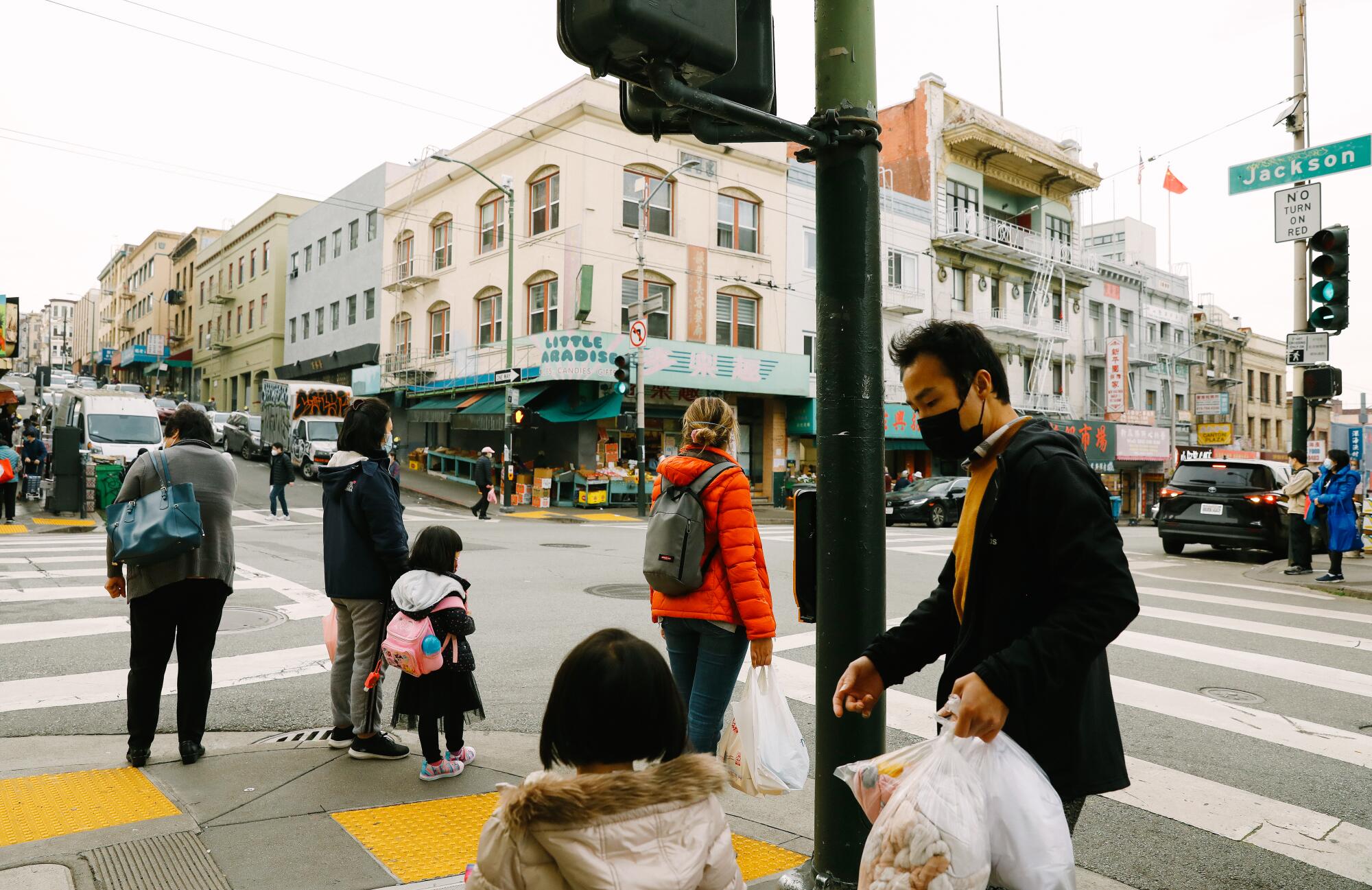 Pedestrians wait at a street corner.