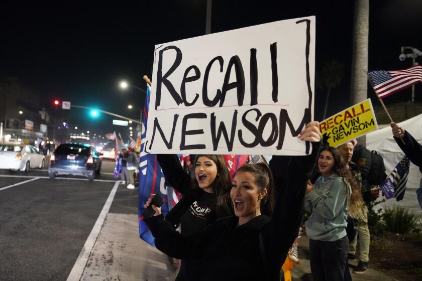 FILE - In this Nov. 21, 2020, file photo, demonstrators shout slogans while carrying a sign calling for a recall on Gov. Gavin Newsom during a protest against a stay-at-home order amid the COVID-19 pandemic in Huntington Beach, Calif. Gov. Newsom is facing a possible recall election as the nation's most populous state struggles to emerge from the coronavirus crisis. Organizers say they have collected more than half of the nearly 1.5 million petition signatures needed to place the recall on the ballot. (AP Photo/Marcio Jose Sanchez, File)