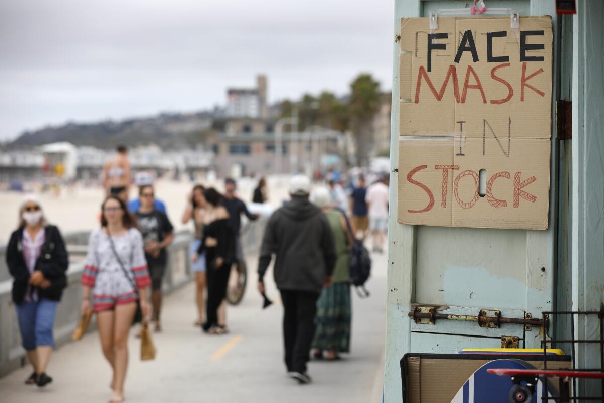 A souvenir shop offers masks for sale as a folks wear  them along the Pacific Beach boardwalk 