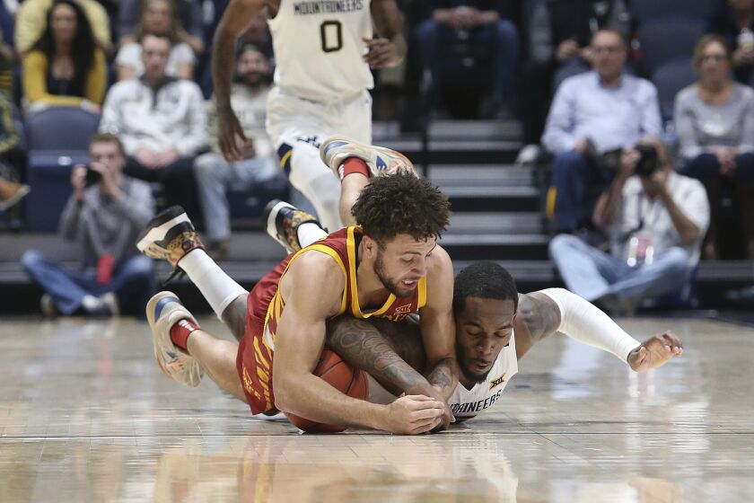 Iowa State guard Gabe Kalscheur, left, and West Virginia forward Jimmy Bell Jr. dive for the ball during the first half of an NCAA college basketball game Wednesday, Feb. 8, 2023, in Morgantown, W.Va. (AP Photo/Kathleen Batten)