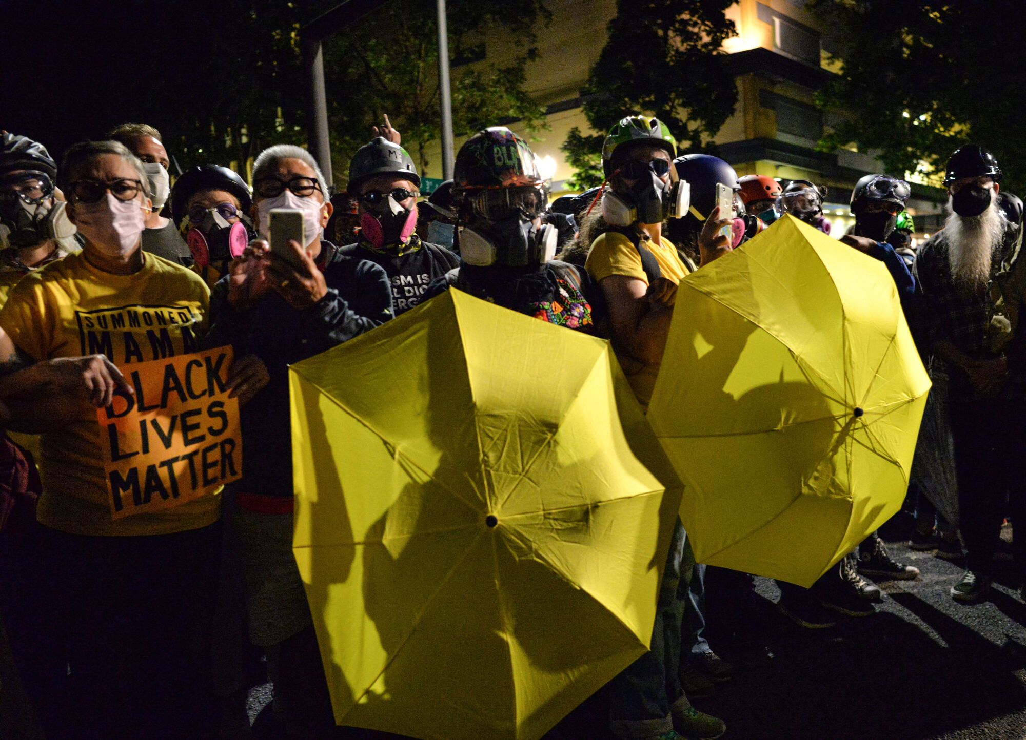 Protesters carry umbrellas as they gather at the Mark O. Hatfield Courthouse in Portland, Ore.