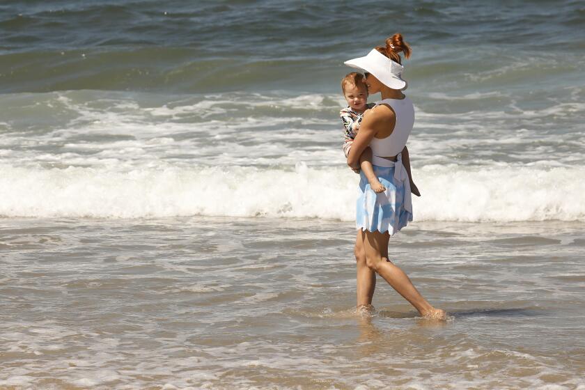 LOS ANGELES, CA - JUNE 11: Amy Paffrath plays with nearly 2-year-old daughter Ember Seeley in the surf at Playa Del Rey Beach Friday morning. The family from Echo Park is spending time at the beach waiting for Mom to arrive at LAX. "We take any chance we can get to go to the beach. We can have a vacation any time we want because we live here," Amy said. People are heading to the beach as temps are starting to climb Friday morning and hot weather is headed to the Southwest corner of the Nation for the coming week. Play Del Rey on Friday, June 11, 2021 in Los Angeles, CA. (Al Seib / Los Angeles Times).