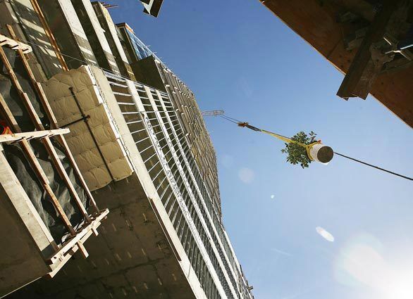 A construction crane lifts a citrus tree to the top of the new Solair development at Wilshire Boulevard and Western Avenue in Los Angeles. Officials gathered Monday on the Solair's roof to mark the "topping off" of the building, the point during construction when the concrete roof is poured and the structure is fully enclosed.