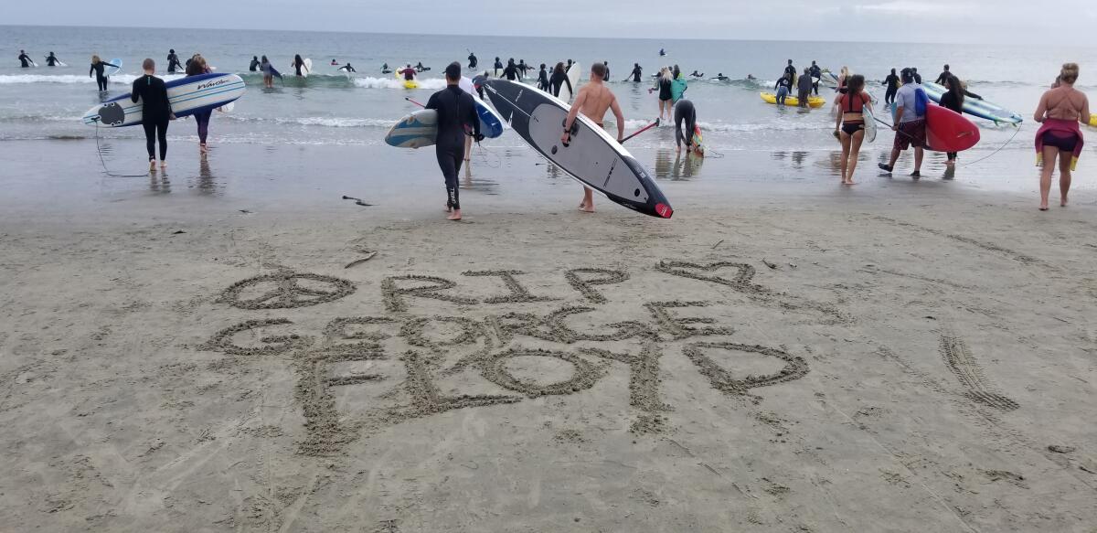 "RIP George Floyd" is written in the sand as community members participate in a paddle-out June 5 at La Jolla Shores.