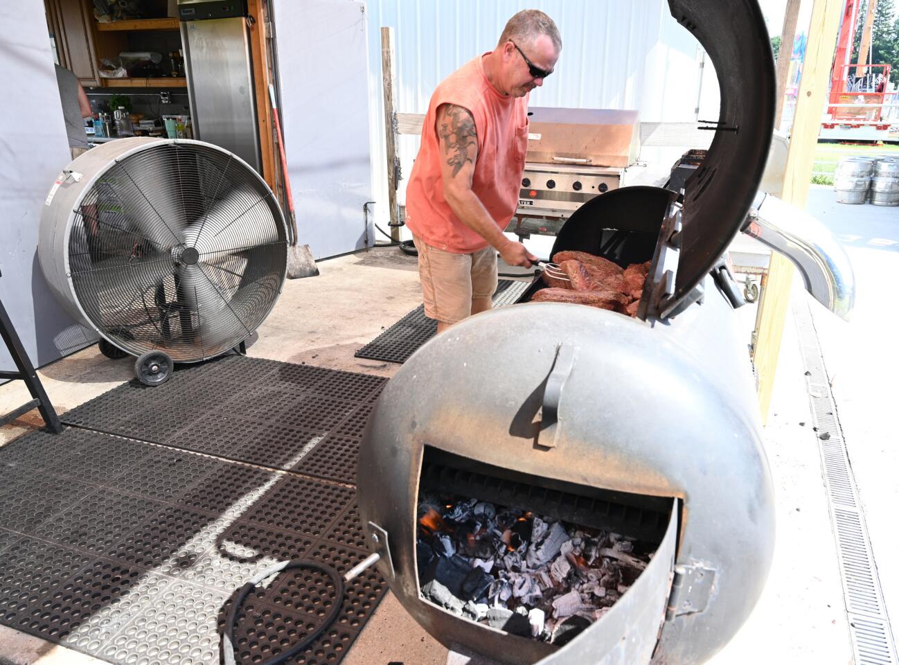 James Haschert deals with the added heat of cooking pit beef on grills near 300 degrees, on top of the near 100 degree temperatures near the opening (4pm) of Reese carnival on Saturday, July 20.