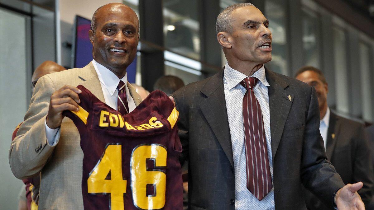 Newly appointed Arizona State football head coach Herm Edwards, right, holds a football jersey with athletic director Ray Anderson during a news conference on Dec. 4, 2017 in Tempe, Ariz.