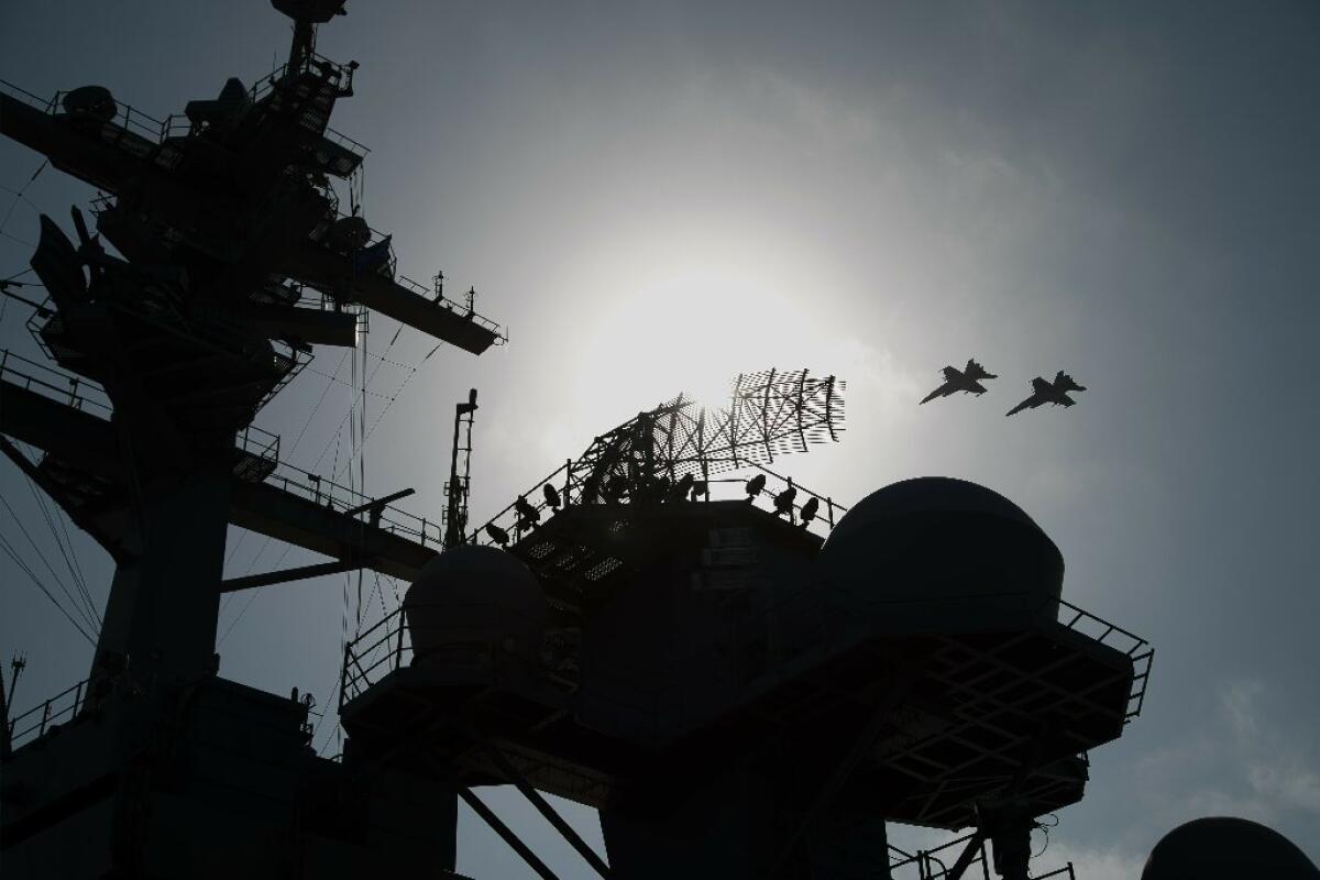F/A-18 fighter jets fly over the deck of the USS Abraham Lincoln, the carrier the White House ordered to the Middle East over a perceived threat from Iran.
