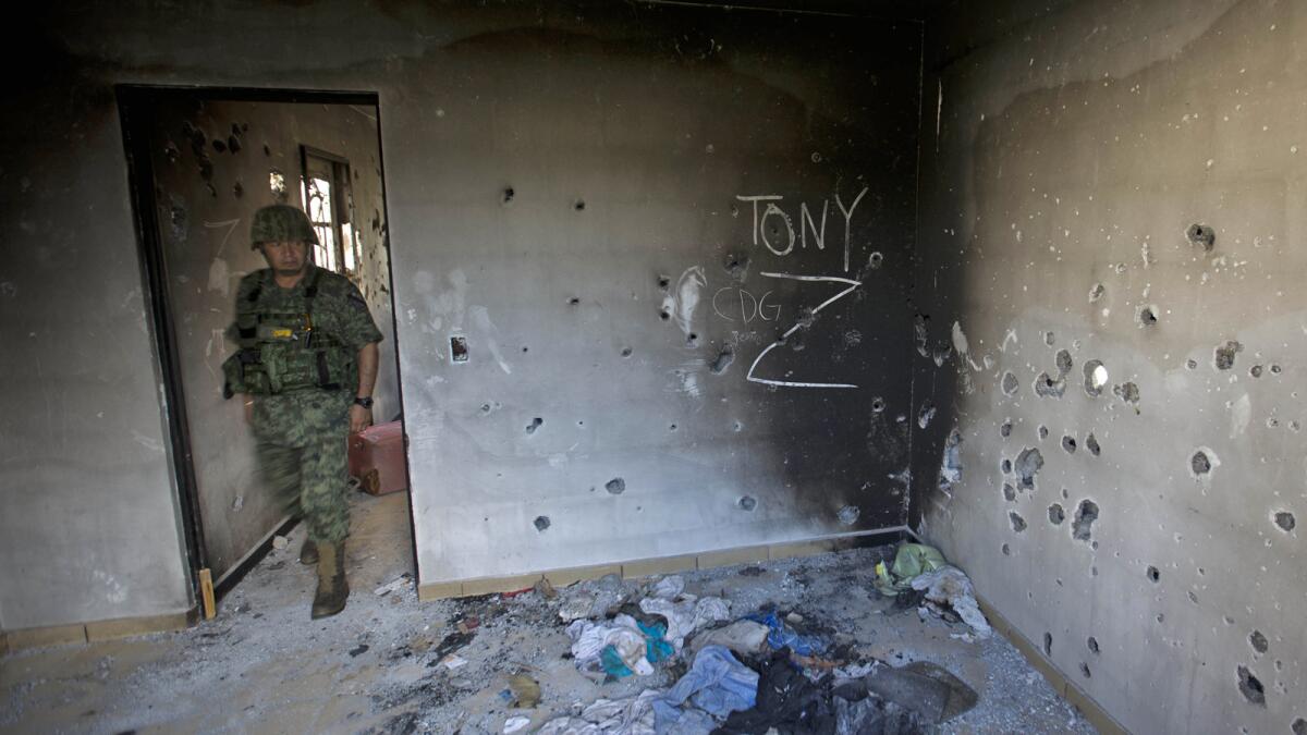 A soldier enters a bullet-riddled home marked with the initials of the Gulf cartel and the Zetas gang in Ciudad Victoria, in Mexico's Tamaulipas state, in September.