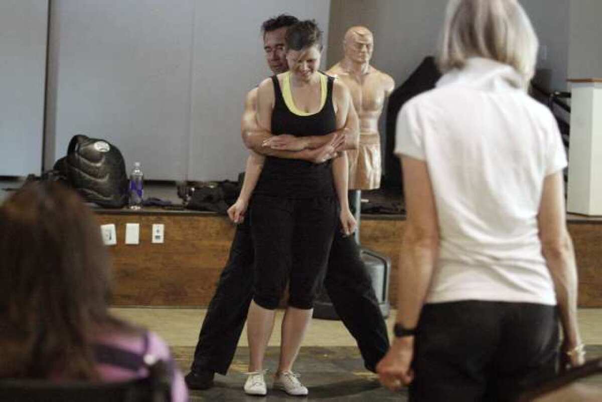 Women's self defense instructor Nelson Nio, left, tries to teach Vivian Geiseler some moves during a self defense class.