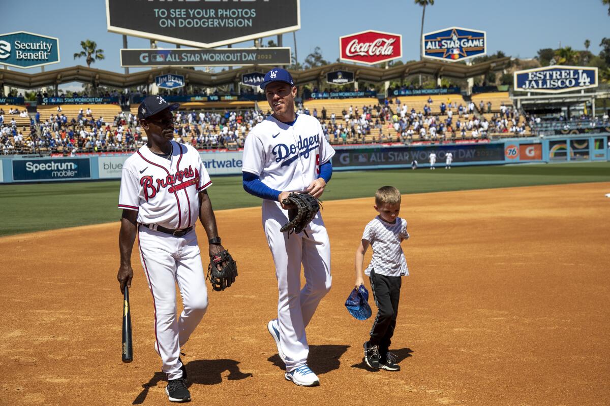 Dodgers first baseman Freddie Freeman, center, walks with his son Freddie II and Braves third base coach Ron Washington.