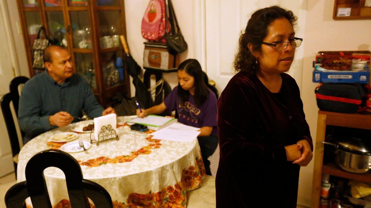 Lorena Zepeda, right, spends a moment with her thoughts while making dinner for her husband, Orlando Zepeda, and daughter Lizbeth, 12, in their home in South Los Angeles.
