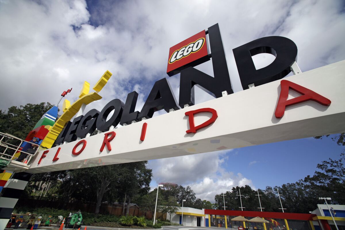 FILE - In this Tuesday, Sept. 27, 2011, file photo, a worker puts finishing touches on the entrance sign at Legoland Florida in Winter Haven, Fla. The Legoland theme park in Florida is planning an expansion next year including new rides, according to plans filed with the city nearest the attraction. The details have not been revealed, but news outlets report Legoland will add about 4.5 acres (1.8 hectares) to its resort near Winter Haven.(AP Photo/John Raoux, File)