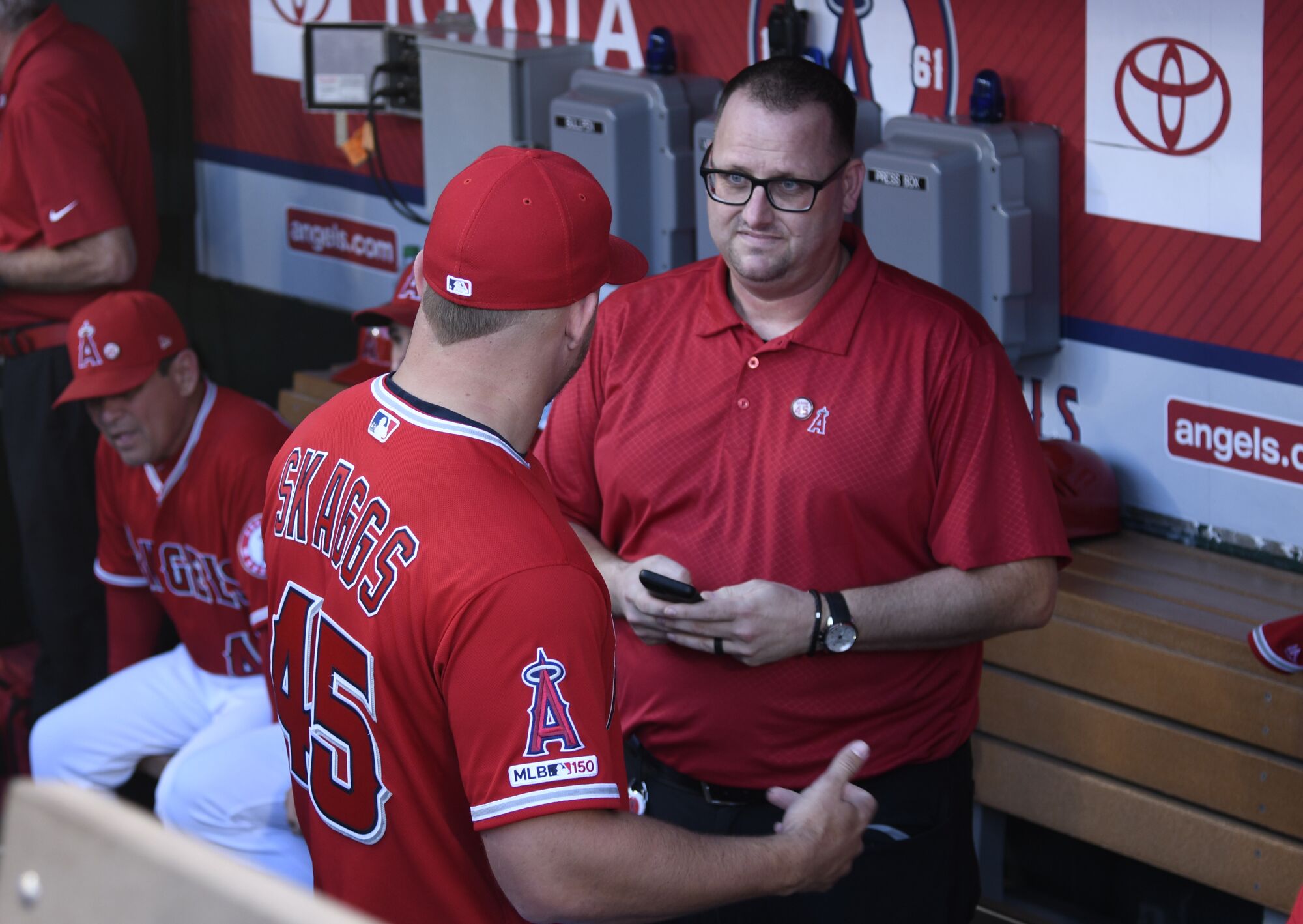 Mike Trout of the Los Angeles Angels speaks to Eric Kay in the dugout.