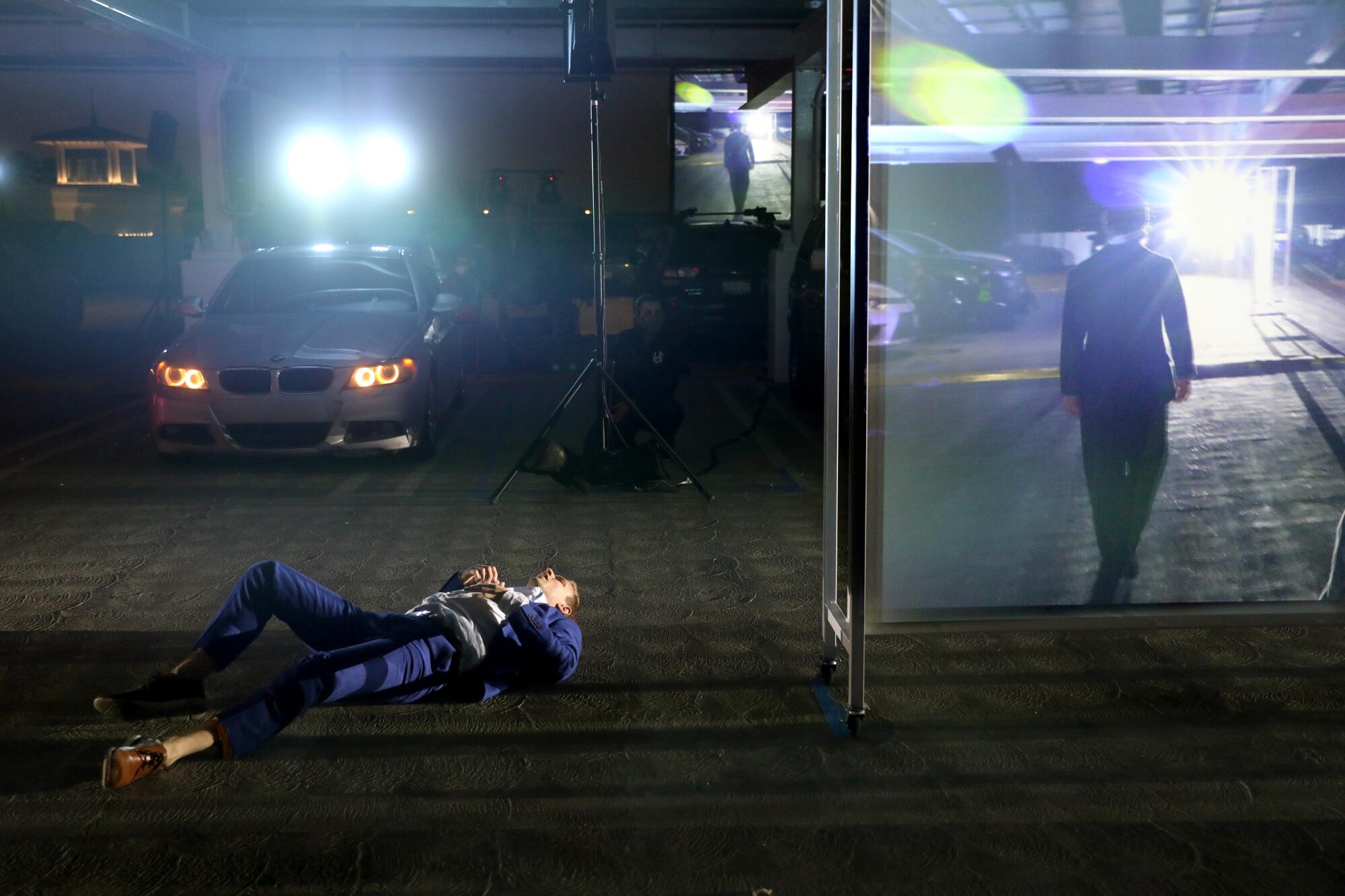 A man in a suit lies on his back on the ground.