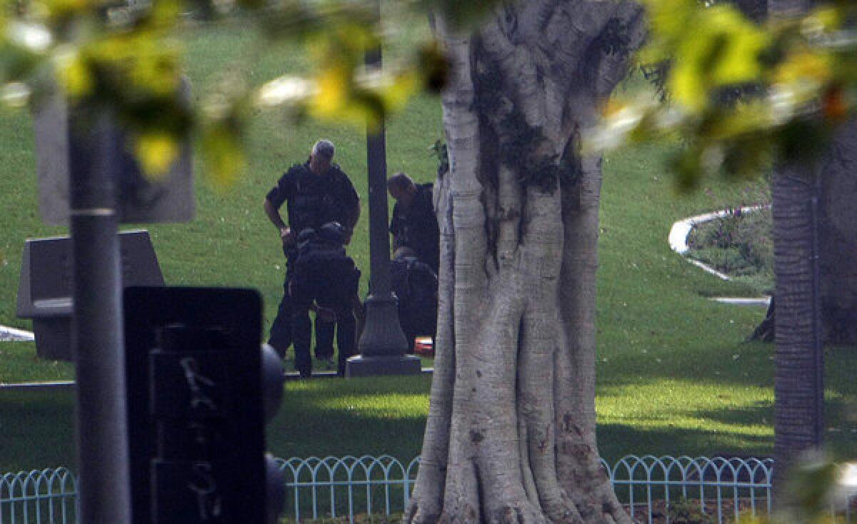 Los Angeles police officers examine an unattended briefcase found on a park bench outside City Hall (Al Seib / Los Angeles Times / July 22, 2013)