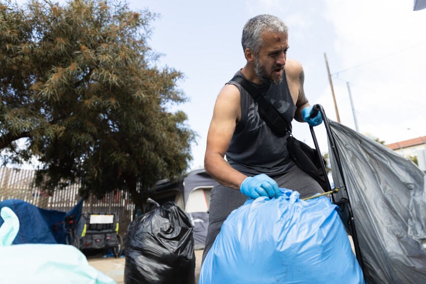 Casper Caspian, 42, loads trashbags onto a cart in downtown San Diego on Thursday.