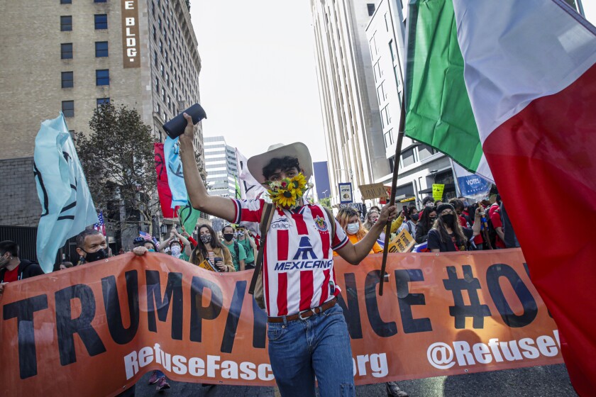 People celebrate in a downtown Los Angeles street with flags, signs and a banner including a man in a cowboy hat.