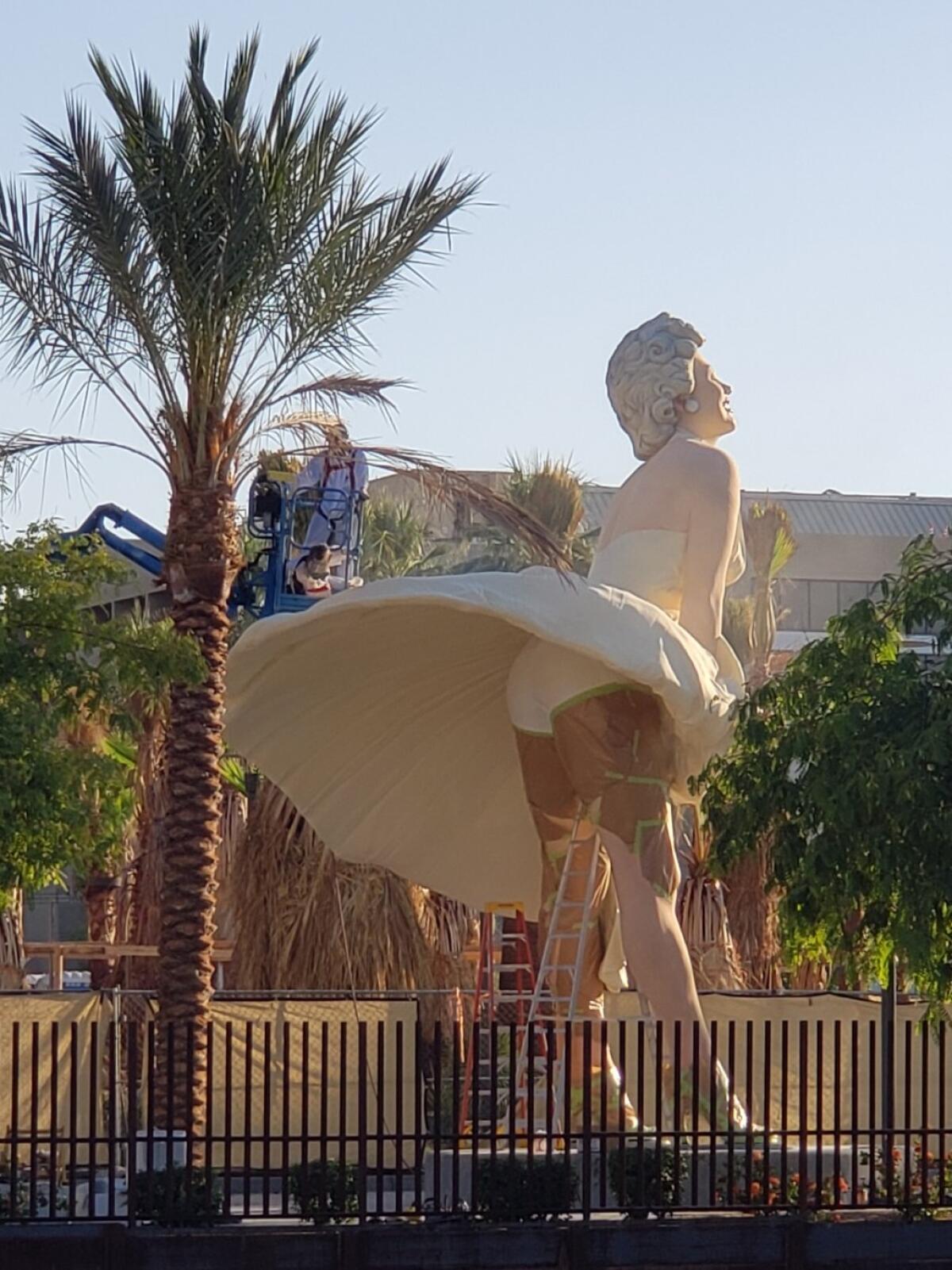 A sculpture of Marilyn Monroe is surrounded by ladders as workers finish installation of the work