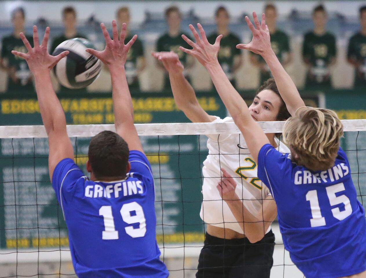 Edison's Caden Satterfield (22) kills the ball past Los Alamitos' blockers Eric Allen (19) Erik Weissinger (15) during Wave League volleyball match on Friday.