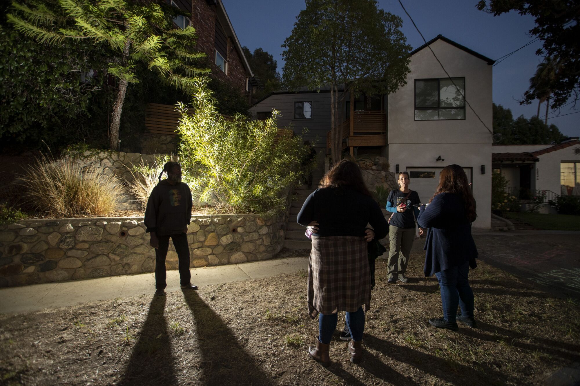 Protesters stand in an Eagle Rock neighborhood after dark.