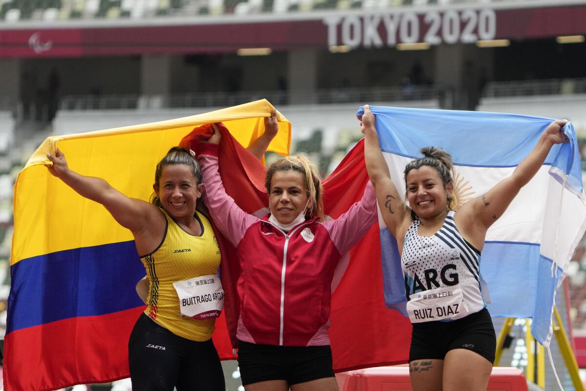 Raoua Tlili of Tunisia, celebrates alongside silver medalist Mayerli Buitrago of Columbia and bronze medalist Ruiz Diaz.