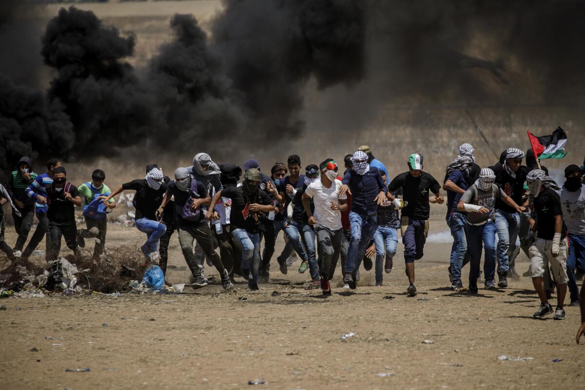 Palestinian protesters run away from tear gas near the border fence separating Israel and the Gaza Strip on May 11.