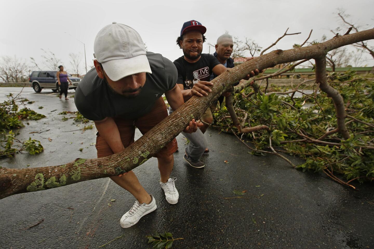 Roberto Flores, left, helps move tree limbs from a San Juan road.