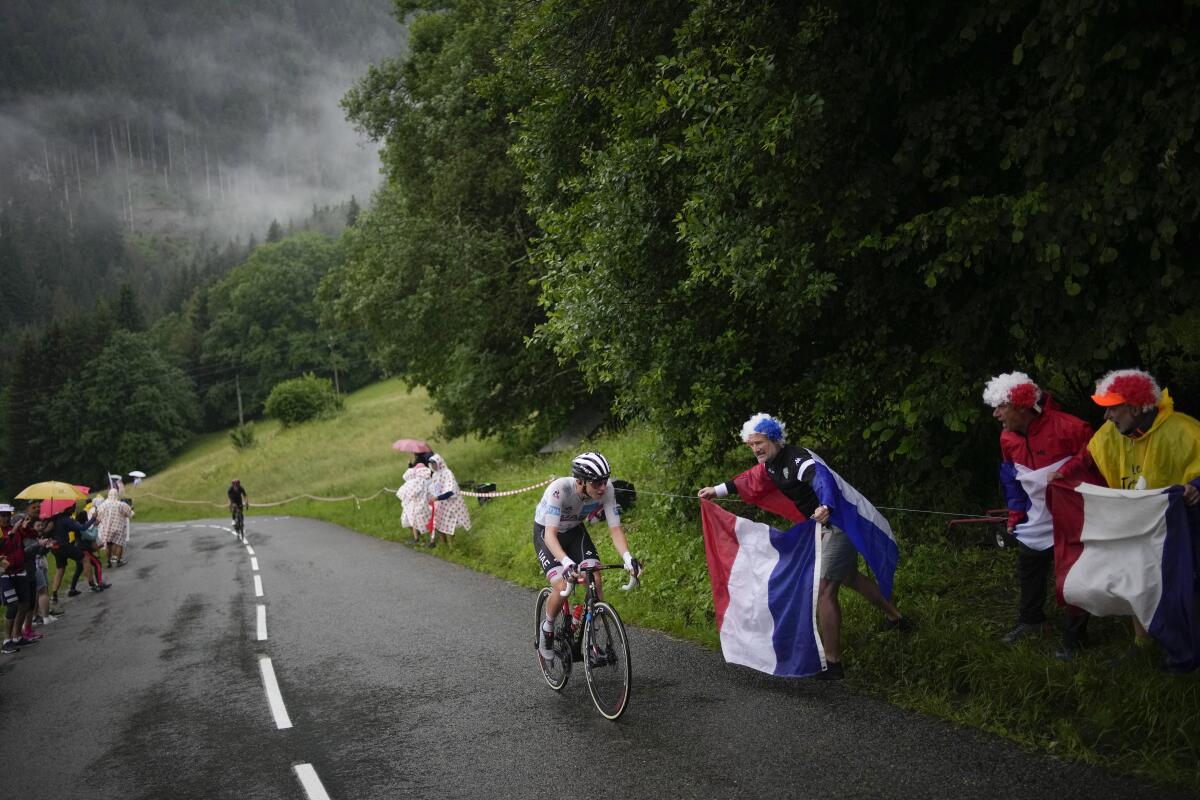 Tadej Pogacar climbs the Col de la Colombiere pass while onlooks watch in colorful outfits