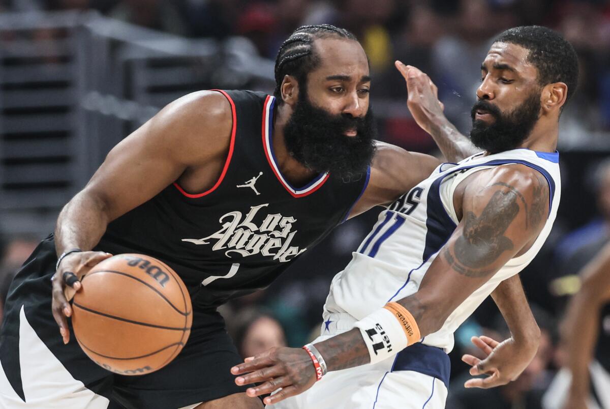 James Harden is tightly guarded by Dallas Mavericks guard Kyrie Irving.