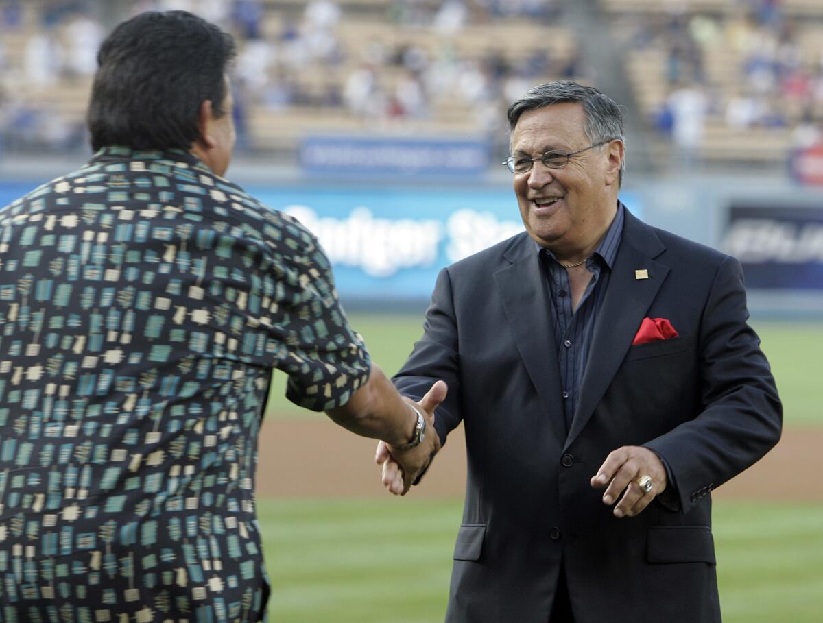 Dodger broadcaster Jaime Jarrin shakes hands with Fernando Valenzuela after throwing out the first pitch before a game in 2008, commemorating Jarrin's 50 years of broadcasting Dodger games.