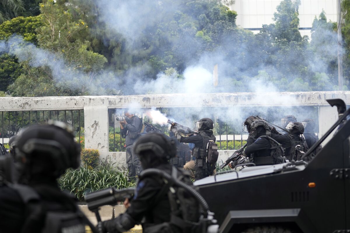 Police fire tear gas to disperse protesters during a rally in Jakarta, Indonesia, Monday, April 11, 2022. Thousands of students marched in cities around Indonesia on Monday to protest against rumors that the government is considering postponing the 2024 presidential election to allow President Joko Widodo to remain in office beyond the two-term legal limit, calling it a threat to the country's democracy. (AP Photo/Tatan Syuflana)