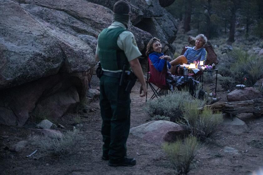 HOLCOMB VALLEY, CA - AUGUST 21: Forest service law enforcement officer Tyler Smith greets campers enjoying a cool mountain evening while on patrol in the Pinnacles area on Friday, Aug. 21, 2020 in Holcomb Valley, CA. (Brian van der Brug / Los Angeles Times)