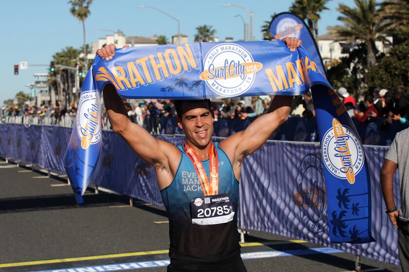 Robert Mohr, 35, of Malibu holds up the Surf City Marathon winning banner after winning the annual Surf City USA Marathon in Huntington Beach, on Sunday, February 6, 2022. (Photo by James Carbone)